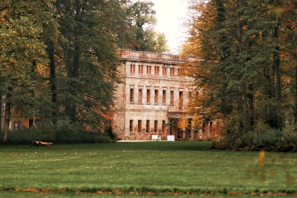 Charming historic palace facade surrounded by lush trees in Zatonie Park, Lubusz Voivodeship, Poland.