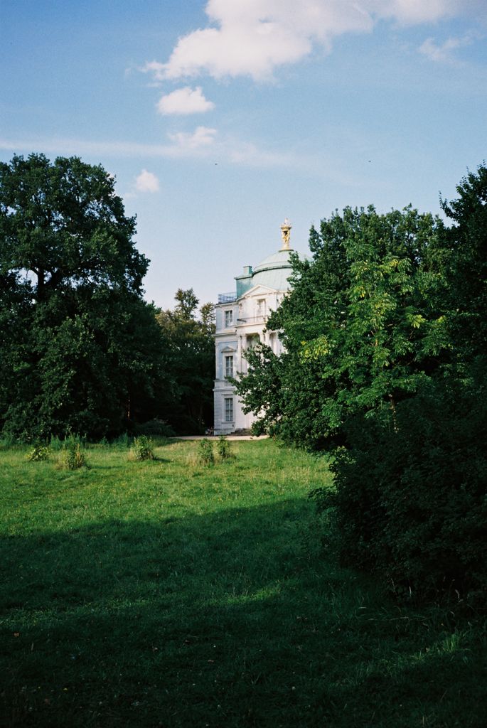 Elegant historical architecture surrounded by lush greenery, captured on a sunny summer day.